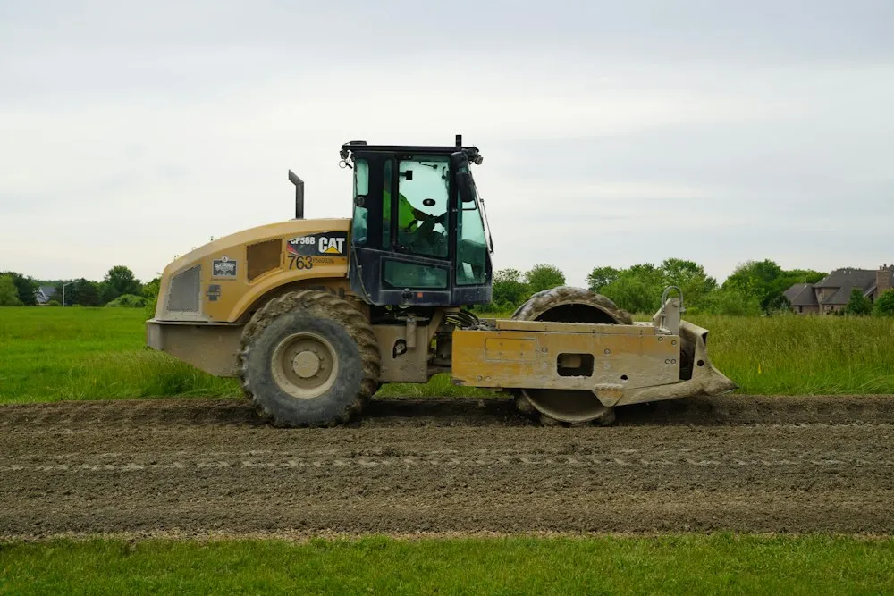 Soil compactor roller compacting a building pad
